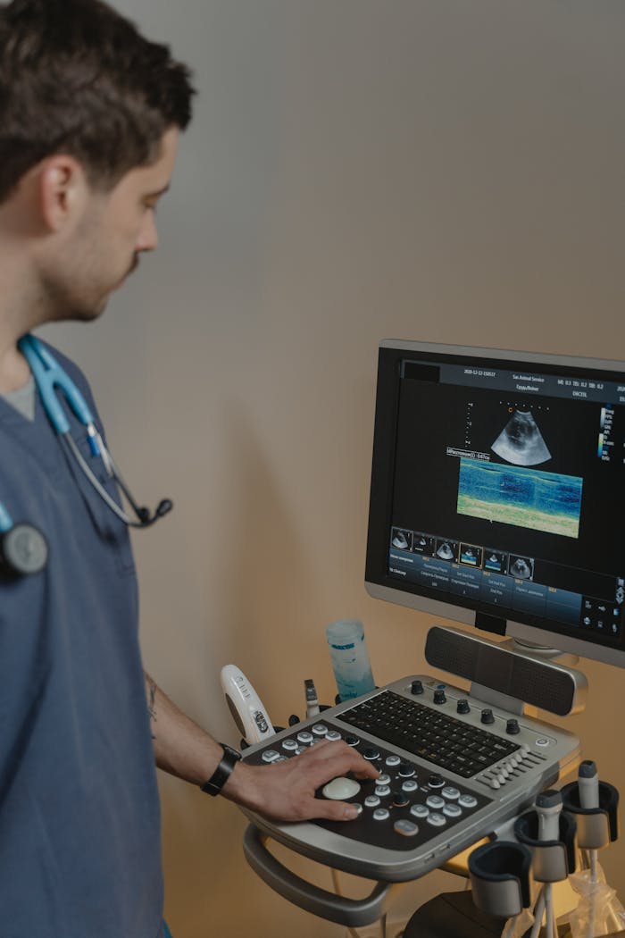 A male veterinarian examines an animal using an ultrasound machine in a clinical setting.
